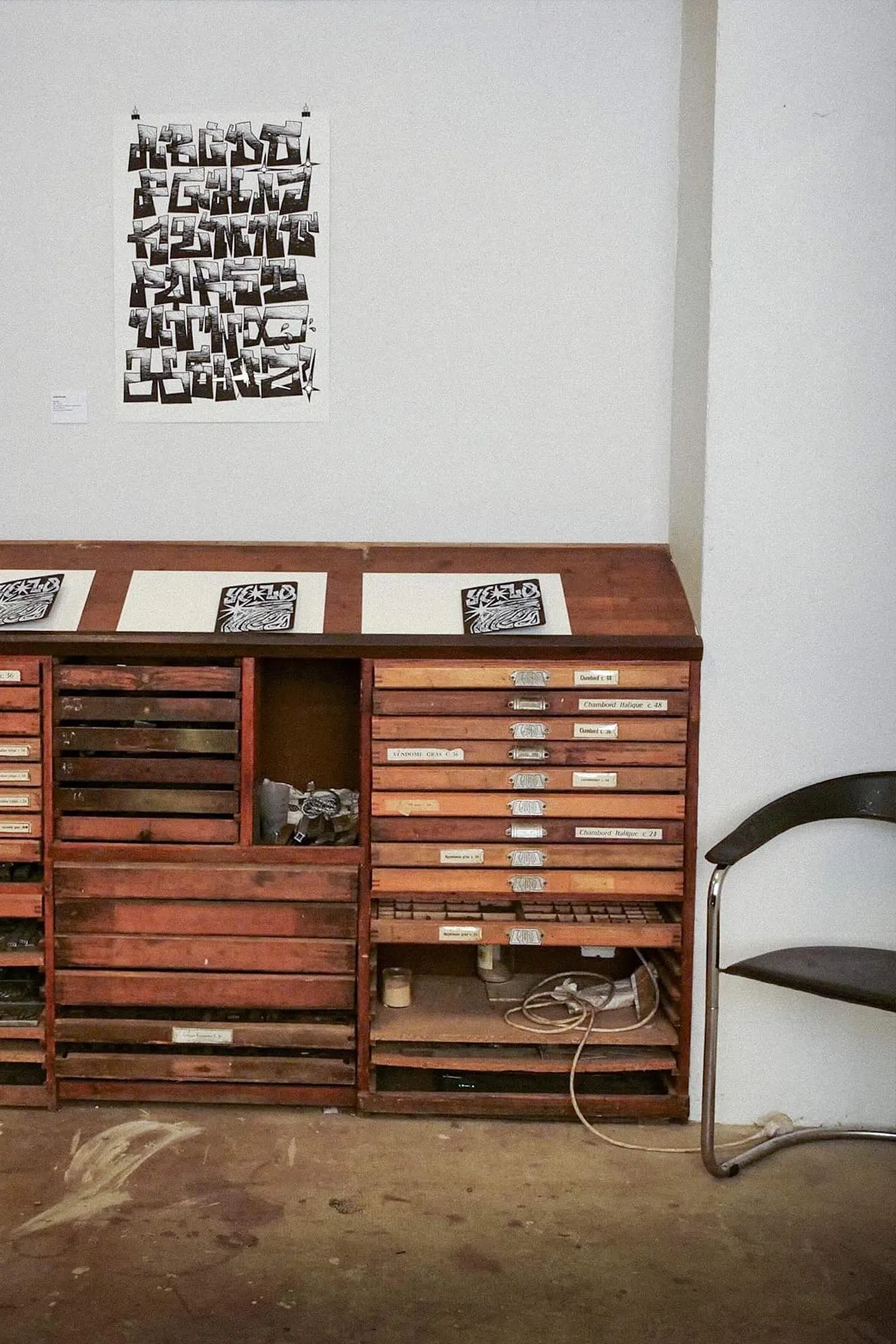 Estampe exposée au-dessus d’un meuble à casse typographique dans l’atelier