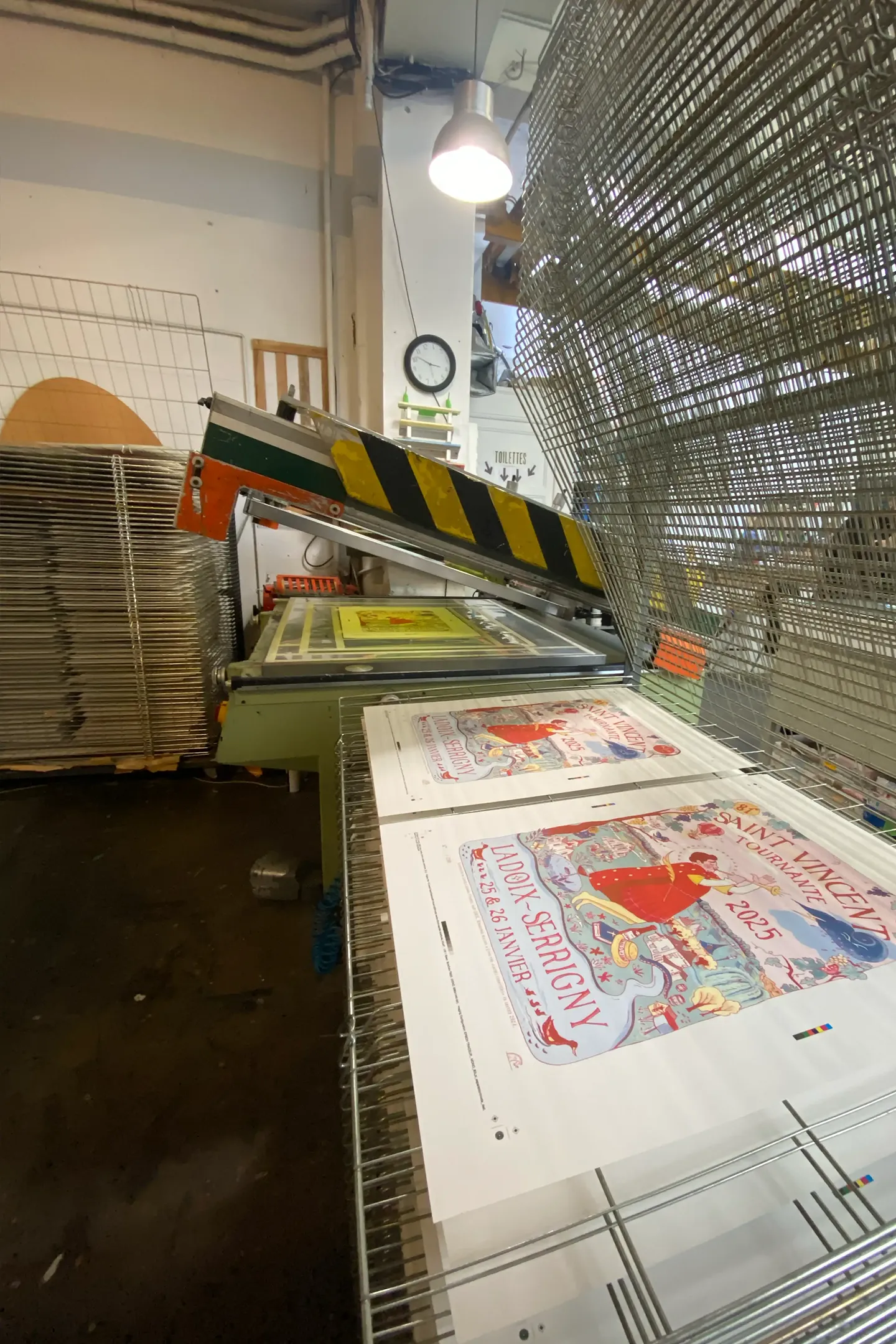 Presse de sérigraphie et claies de séchage dans l’atelier